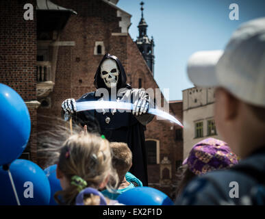 Kinder mit blauen Ballons sehen lustig Leistung in Polen. Schauspieler zeigt Sensenmann. Festival auf dem zentralen Platz in Krakau, Po Stockfoto