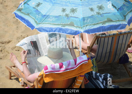 Berlin, Deutschland. 5. Juli 2015. Eine Frau liest ein Buch unter dem Sonnenschirm im Strandbad am Wannsee in Berlin, Deutschland, 5. Juli 2015. Foto: RAINER JENSEN/Dpa/Alamy Live-Nachrichten Stockfoto