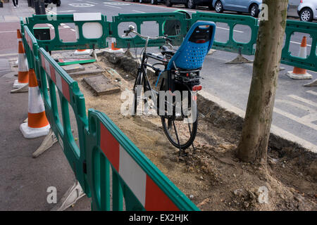 Ein Damen Fahrrad gesperrt, um einen Beitrag, eingeschlossen und blockiert während Pflaster Ersatz Werke in Südlondon. Stockfoto