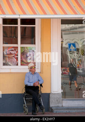 Alter Mann sitzt auf seinen Walker zum Ausruhen im Schatten an einem Sommertag auf der quadratischen Bellamy in Vlissingen Stockfoto