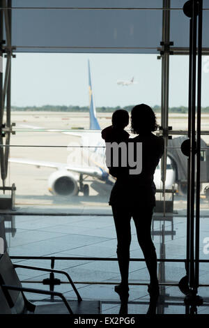 Baby am Flughafen; Mutter hält Baby Sohn, die auf Flugzeuge wartet, die auf das Einsteigen warten, Abflüge, Flughafen Barcelona, Spanien, Europa Stockfoto