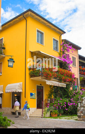 Malerische gelbes bemaltes Haus abgedeckt in schöne, lebendige Blumen in Sirmione, Gardasee, Italien Stockfoto