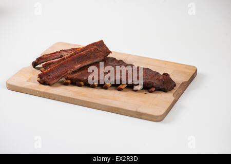 Glasierte Spareribs auf Holzplatte auf weißem Hintergrund Stockfoto