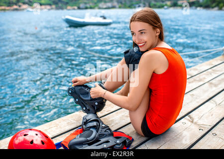 Frau in Sportkleidung mit skating Rollen auf dem pier Stockfoto