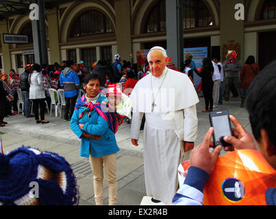 La Paz, Bolivien, 5. Juli 2015. Eine lokale Dame und ihr Baby posieren für ein Foto mit einem lebensgroßen Karton-Ausschnitt von Papst Franziskus bei einer Veranstaltung, um seinen bevorstehenden Besuch in Bolivien zu feiern. Papst Franziskus wird La Paz am 8. Juli während seiner 3-tägigen Reise nach Bolivien besuchen. Stockfoto