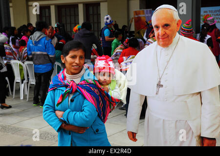 La Paz, Bolivien, 5. Juli 2015. Eine lokale Dame und ihr Baby posieren für ein Foto mit einem lebensgroßen Karton-Ausschnitt von Papst Franziskus bei einer Veranstaltung, um seinen bevorstehenden Besuch in Bolivien zu feiern. Papst Franziskus wird La Paz am 8. Juli während seiner 3-tägigen Reise nach Bolivien besuchen. Stockfoto