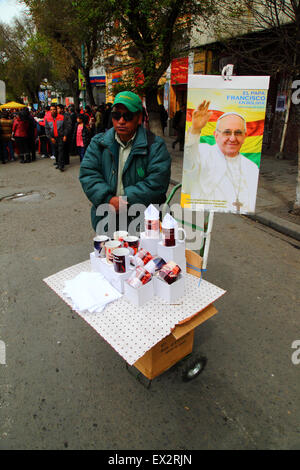 La Paz, Bolivien, 5. Juli 2015. Ein Mann verkauft Papst Franziskus Becher auf einer Straße auf der Avenida 16 de Julio/El Prado stall in er Innenstadt. Papst Franziskus besuchen La Paz am 8. Juli während seines 3-tägigen Reise nach Bolivien. Stockfoto