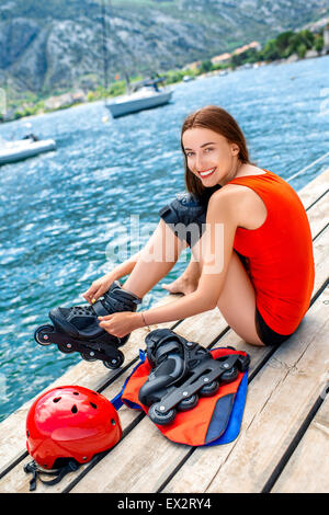 Frau in Sportkleidung mit skating Rollen auf dem pier Stockfoto