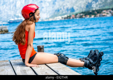 Frau in Sportkleidung mit skating Rollen auf dem pier Stockfoto