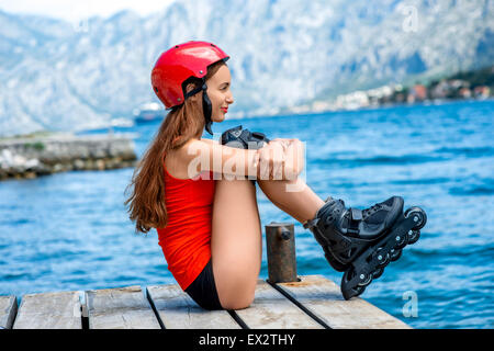 Frau in Sportkleidung mit skating Rollen auf dem pier Stockfoto