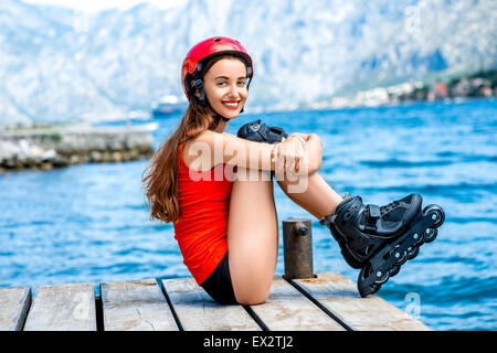 Frau in Sportkleidung mit skating Rollen auf dem pier Stockfoto