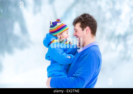 Junger Vater spielt mit seinem lustigen Baby in einem verschneiten park Stockfoto