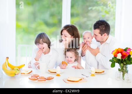 Glückliche junge Familie mit drei Kindern - Teenager Boy, niedlichen Kleinkind Mädchen und ein neugeborenes Baby - Frühstück Stockfoto