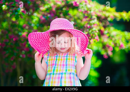 Kleine süße Mädchen mit Blumen. Kind einen rosa Hut spielen in einem blühenden Sommer Garten. Kinder im Garten. Stockfoto