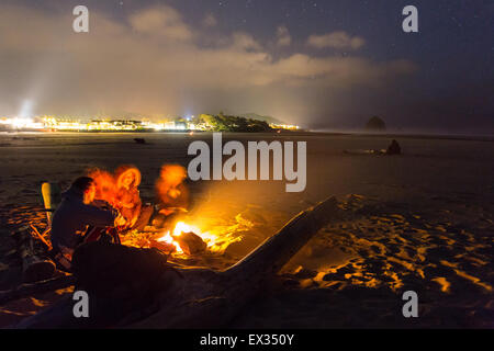 Ein paar Freunde versammeln sich um ein Strand-Lagerfeuer unter dem Sternenhimmel in Cannon Beach, Oregon. Stockfoto
