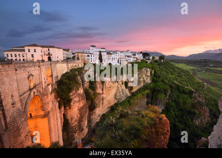 Roter Himmel Abendlicht auf weißen Gebäuden und orange Klippen bei El Tajo Schlucht Ronda Spain bei der Guadalevin River gorge Stockfoto