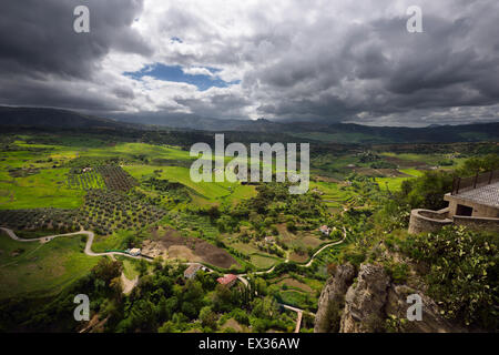 Gefleckte Sonnenschein auf grünen Feldern im Tal unterhalb der Berg Stadt Ronda Spain Stockfoto