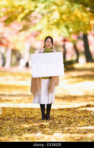 Ältere Japanerin mit Whiteboard in einem Stadtpark im Herbst Stockfoto