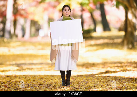 Ältere Japanerin mit Whiteboard in einem Stadtpark im Herbst Stockfoto