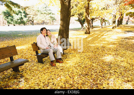 Senior japanische paar sitzt auf einer Bank im Stadtpark Stockfoto