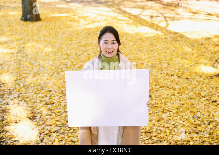 Ältere Japanerin mit Whiteboard in einem Stadtpark im Herbst Stockfoto