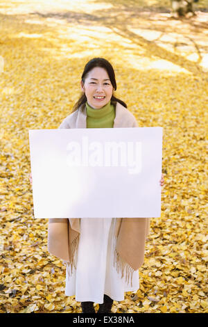 Ältere Japanerin mit Whiteboard in einem Stadtpark im Herbst Stockfoto