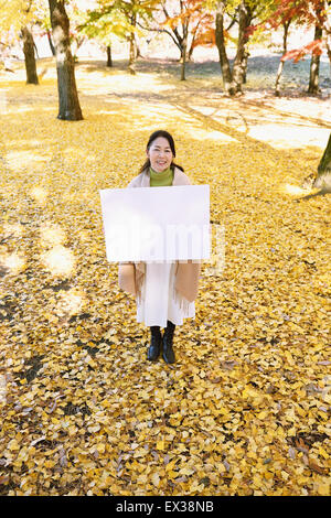 Ältere Japanerin mit Whiteboard in einem Stadtpark im Herbst Stockfoto