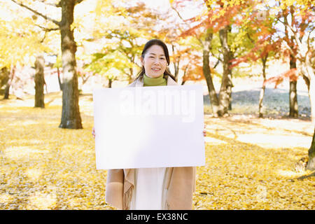 Ältere Japanerin mit Whiteboard in einem Stadtpark im Herbst Stockfoto