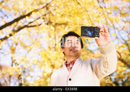 Ältere Japaner nehmen ein Selbstporträt in einem Stadtpark im Herbst Stockfoto