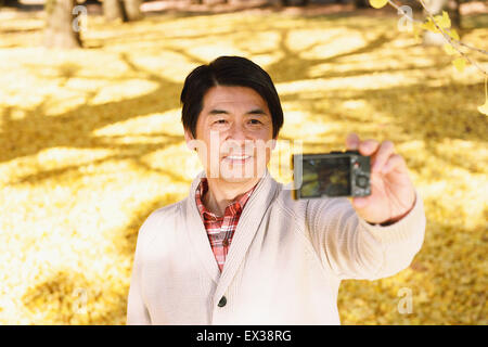 Ältere Japaner nehmen ein Selbstporträt in einem Stadtpark im Herbst Stockfoto