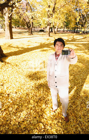 Ältere Japaner nehmen ein Selbstporträt in einem Stadtpark im Herbst Stockfoto