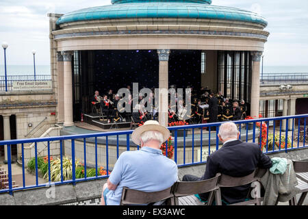 sitzen zwei ältere Männer, die gerade einer Band spielt Musik in Eastbourne Bandstand Stockfoto