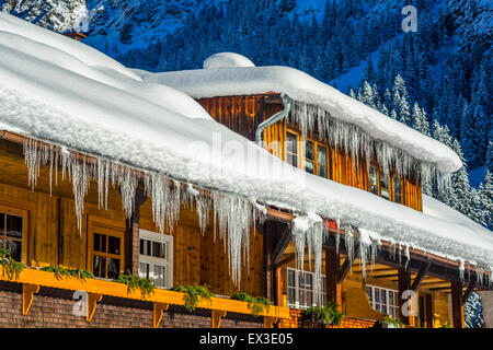 Lange Eiszapfen hängen von Schnee bedeckten Bauernhaus Dach, Stillachtal, Oberstdorf, Allgäu, Bayern, Deutschland Stockfoto