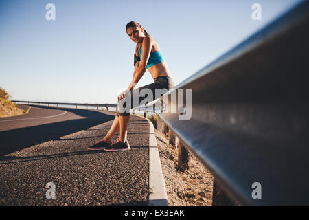 Entspannung nach einem Outdoor-Training junge Frau müde. Läufer nach Morgenlauf auf Straße Geländer ruht. Stockfoto