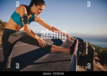 Weibliche Läufer ihre Beine im Freien vor der Ausführung. Frau, Bein Stretch-Übungen auf Straße Geländer. Stockfoto