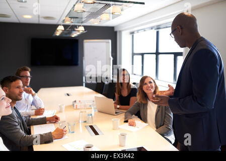 Schwarzer Mann an der Spitze ein Treffen mit einer Gruppe von Führungskräften in einem Konferenzraum Stockfoto