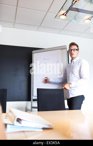 Junge weiße männliche executive zeigt ein Diagramm auf einem Whiteboard führt ein Treffen Stockfoto