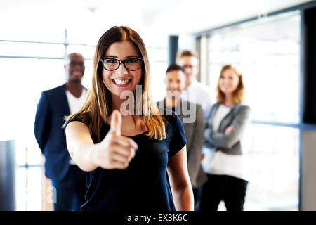 Junge weiße weibliche executive stand vor Kollegen machen Daumen hoch Zeichen. Stockfoto