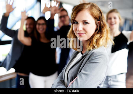 Weibliche Weiße executive stand vor der Kollegen mit ihren Armen in der Luft Stockfoto