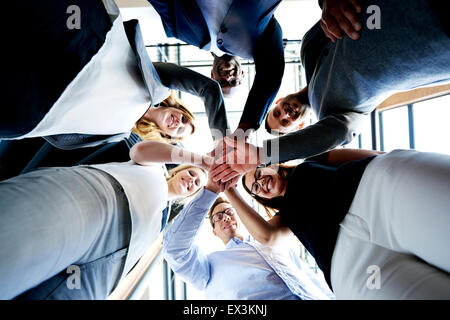 Gruppe junger Führungskräfte stehen in einem Kreis mit Händen zusammen auf der Suche nach unten. Stockfoto