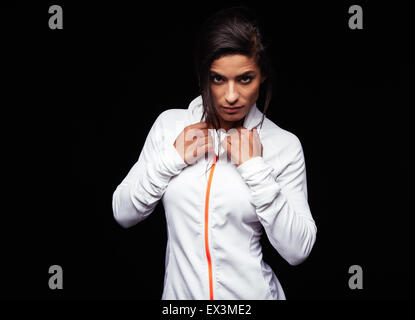 Porträt der selbstbewusste junge Frau trägt Sport Jacke Blick in die Kamera vor schwarzem Hintergrund. Fitness weibliches Modell. Stockfoto