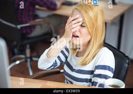 Frustrierte junge Frau sitzt am Tisch im Büro Stockfoto