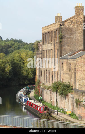 Ein Radfahrer übergibt festgemachten schmale Boote und viktorianischen Gebäude am Regents Kanal in der Nähe von Kings Cross im Zentrum von London Stockfoto