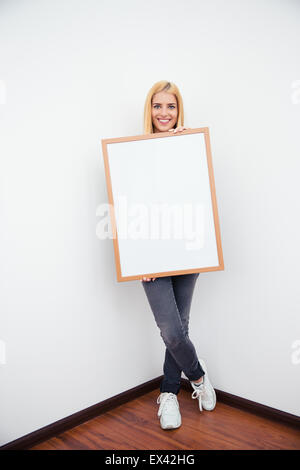 Voller Länge Porträt einer lächelnden lässig Frau hält leere Kammer und Blick in die Kamera Stockfoto