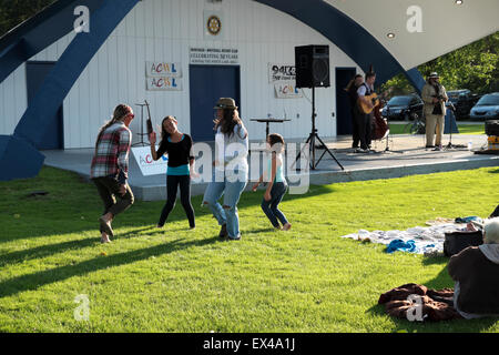 Zwei Frauen und zwei Mädchen tanzen während eines Konzerts der Gemeinschaft in den Bandshell in Montague, Michigan, USA. Stockfoto