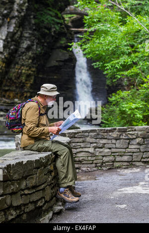 Ein Mann schaut auf eine Wanderkarte mit einem Wasserfall im Hintergrund, in Watkins Glen State Park, New York Stockfoto