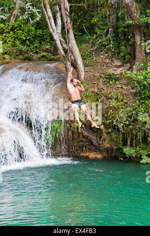 Vertikale Porträt eines Touristen in Wasserfällen im Topes de Collantes Nationalpark in Kuba aus einer Liane schwingen. Stockfoto