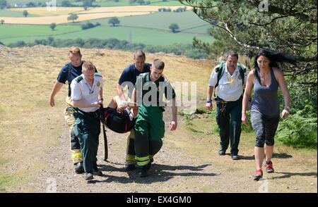 Shropshire Rettungsdienst und Shropshire Feuer und Rettung Offiziere tragen verletzte Frau zurück zum Krankenwagen Wrekin Hill Uk Stockfoto