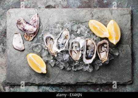 Öffnen von Austern auf Steinplatte mit Eis und Zitrone Stockfoto