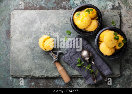 Mango-Eis-Sorbet mit Minze und Löffel für Eis auf Stein Schiefer Hintergrund Stockfoto